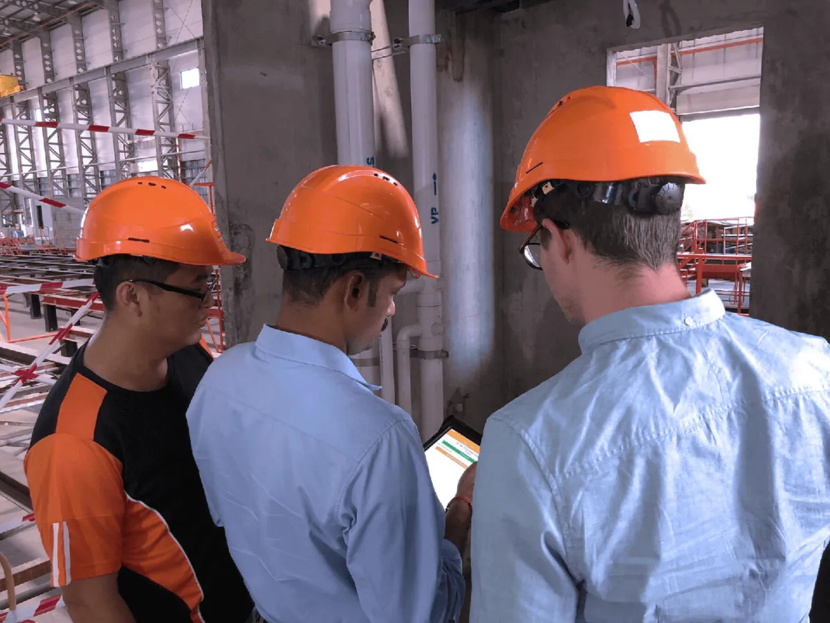 Construction team reviewing site management data on tablet at job site