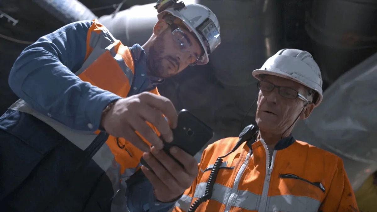 Construction workers reviewing site reports on tablet device during inspection